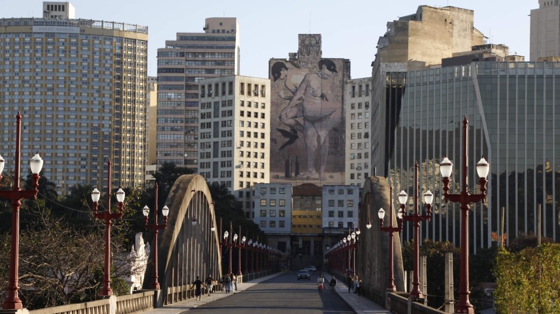 Foto do viaduto Santa Tereza, em Belo Horizonte. Uma arte em um prédio alto aparece ao fundo.